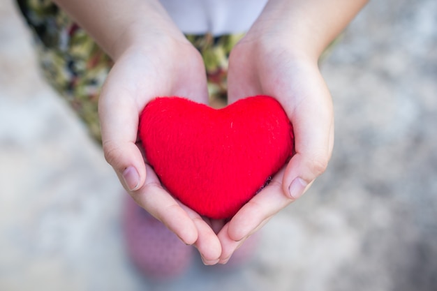 Piccole mani del bambino che tengono il cuore