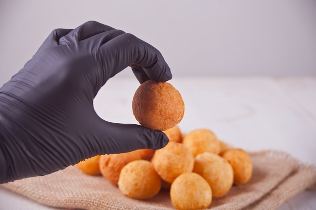 Piccole palline di ciambelle di ricotta fatte in casa appena sfornate e mano di donna in guanti neri