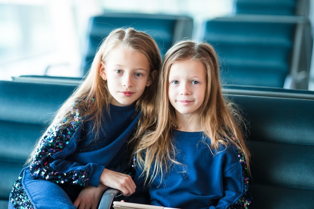 Piccole ragazze adorabili in aeroporto in attesa di salire vicino alla grande finestra