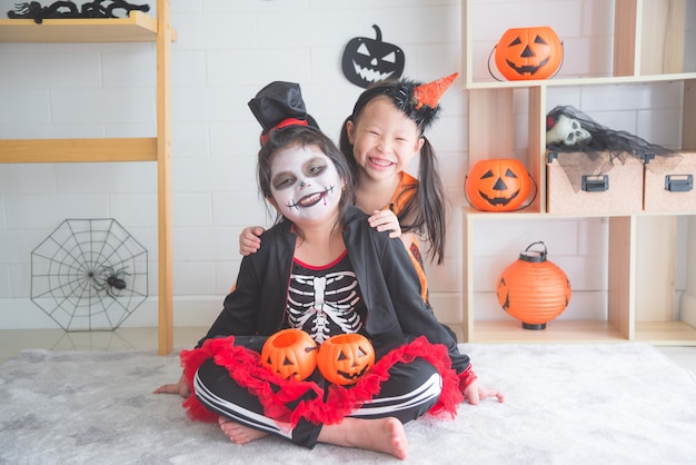 Piccole ragazze asiatiche che si siedono e sorridono nella sala