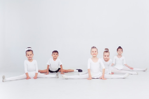 Piccole ragazze e ragazzi delle ballerine che fanno le spaccature sullo spazio bianco della copia del pavimento