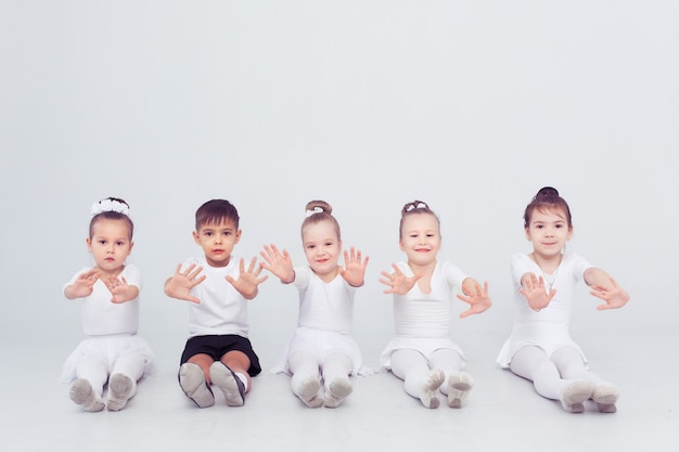 Piccole ragazze e ragazzi delle ballerine che fanno le spaccature sullo spazio bianco della copia del pavimento