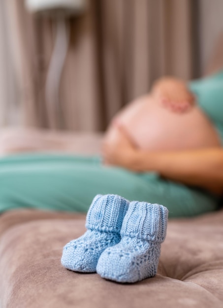 Piccole scarpe per il nascituro nel ventre Giovane donna incinta con scarpe per bambini piccoli