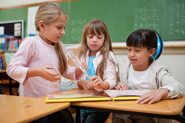 Piccole studentesse che leggono una fiaba al loro compagno di classe