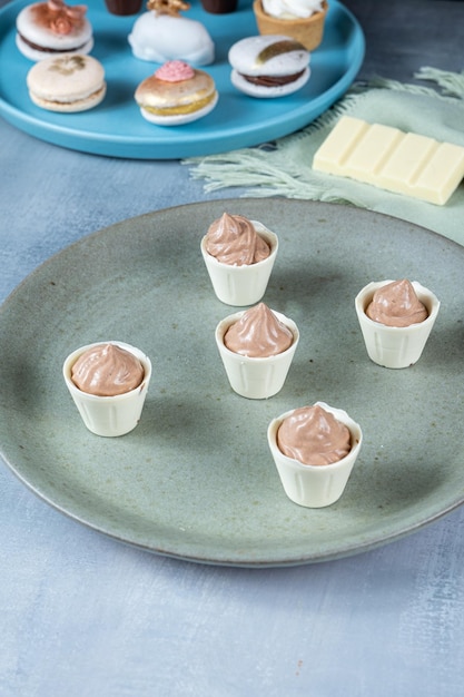 Piccole tazze di cioccolato bianco ripiene di mousse al cioccolato al latte su un piatto verde