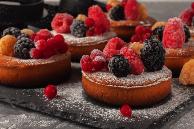 Piccole torte di frutta fatte in casa fresche con lamponi, ribes e more sul tavolo