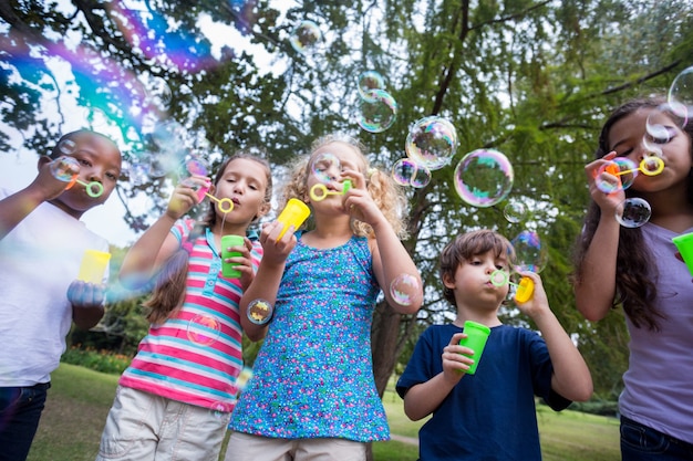 Piccoli amici che soffiano bolle nel parco