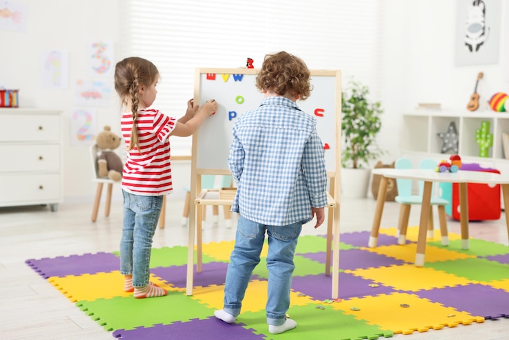 Foto piccoli bambini carini che imparano l'alfabeto con lettere magnetiche a bordo all'asilo