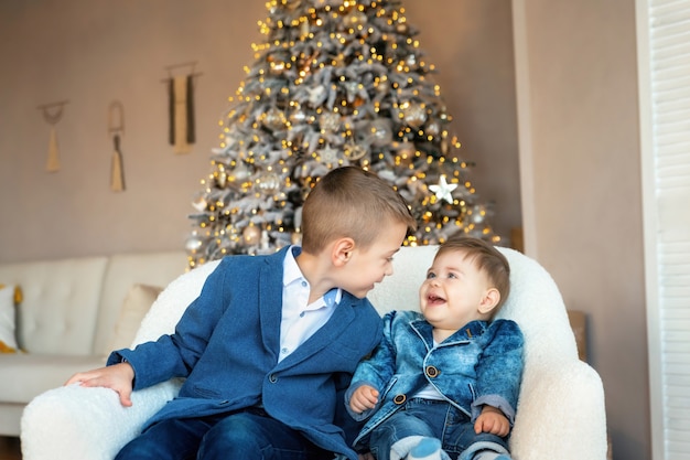 Piccoli bambini che ridono felici. Fratelli amorevoli di buon umore in attesa del Natale. Bambini adorabili felici che si divertono durante le vacanze invernali vicino all'albero di Natale decorato a casa.