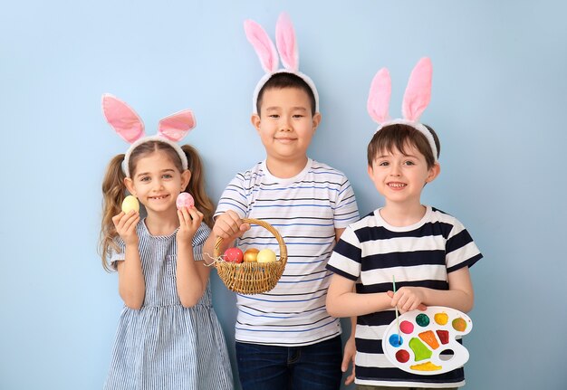 Piccoli bambini con le uova di Pasqua e la tavolozza della pittura sulla superficie di colore