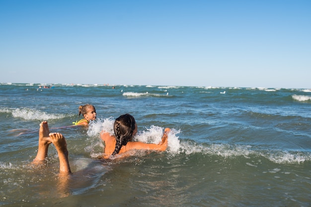 Piccoli bambini felici che nuotano nel mare in una calda giornata estiva soleggiata