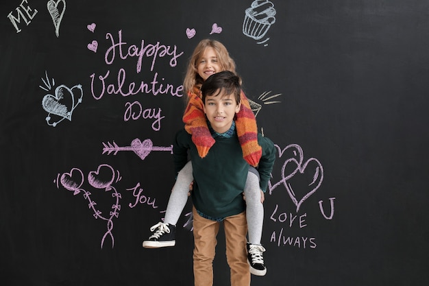 Piccoli bambini felici vicino alla parete scura. Festa di San Valentino