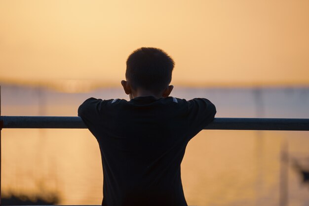 Piccoli bambini in piedi guardando verso il mare mentre il tramonto.