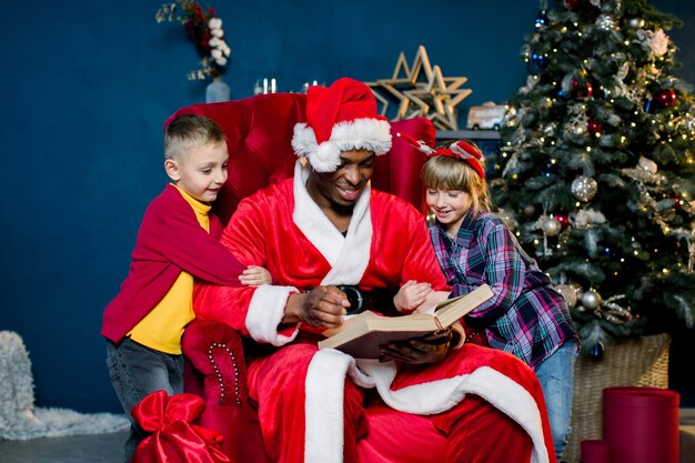 Piccoli bei bambini ascoltano la storia che legge Babbo Natale