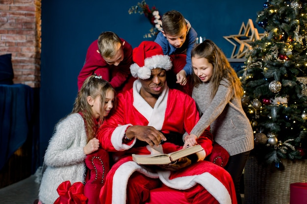 Piccoli bei bambini ascoltano la storia che legge Babbo Natale