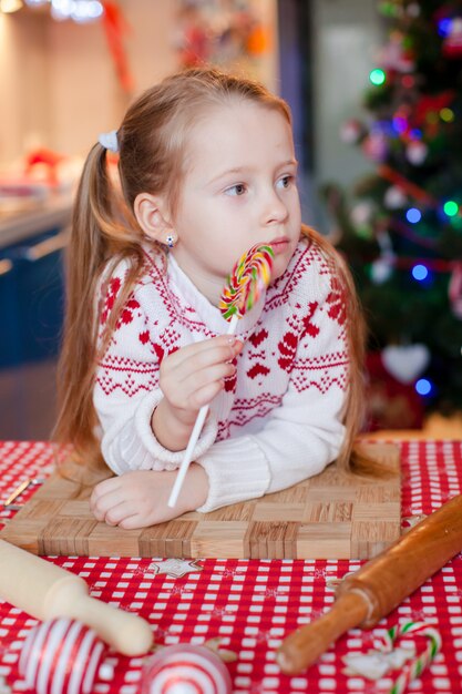 Piccoli biscotti adorabili di Natale di cottura della ragazza a casa