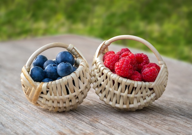 Piccoli cestini di frutti di bosco su una vecchia tavola di legno