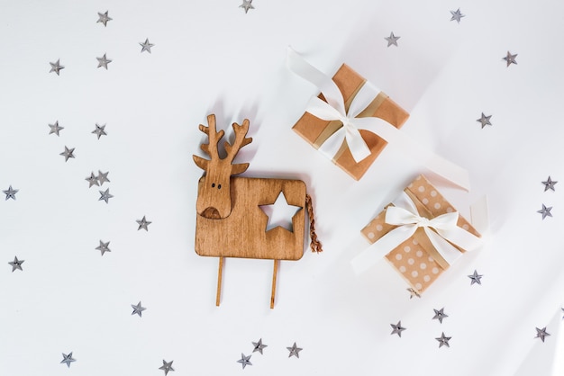 Piccoli contenitori di regalo con i cervi di legno d'annata contro una celebrazione scintillante di Natale delle stelle.