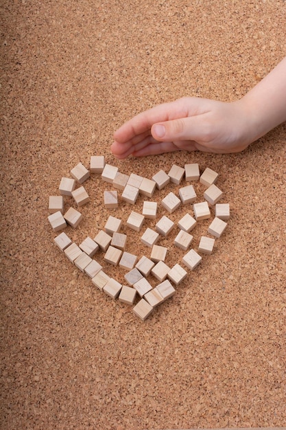 Piccoli cubi di legno formano la forma di un cuore o il simbolo e la mano di San Valentino