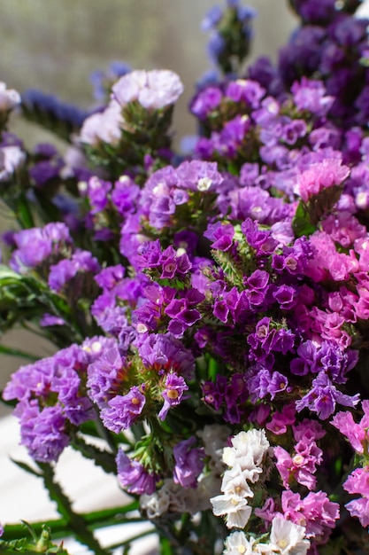 Piccoli fiori secchi luminosi statice kermek viola bianco bouquet verticale
