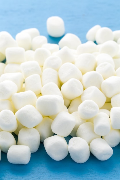 Piccoli marshmallow bianchi rotondi su sfondi blu.