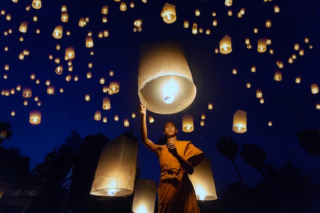 Piccoli monaci hanno acceso un fuoco di lanterne galleggianti, lanterne galleggianti di monaci buddisti thailandesi