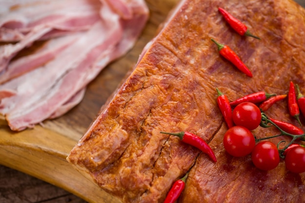 Piccoli peperoni rossi sulla carne. Strisce di pancetta cruda e pomodori. Manzo gustoso cucinato in casa. Aroma che risveglia l'appetito.