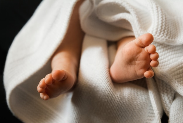 Piccoli piedi di un neonato sdraiato sulla coperta bianca