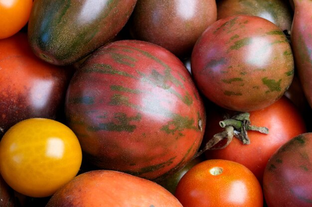 Piccoli pomodori maturi multicolori di diverse varietà giacciono su una macrofotografia ravvicinata di un tavolo di legno