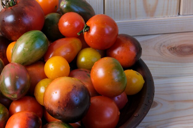 Piccoli pomodori maturi multicolori di diverse varietà giacciono su una macrofotografia ravvicinata di un tavolo di legno