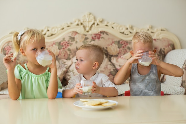 Piccoli ragazzi e ragazza che beve latte alla tavola