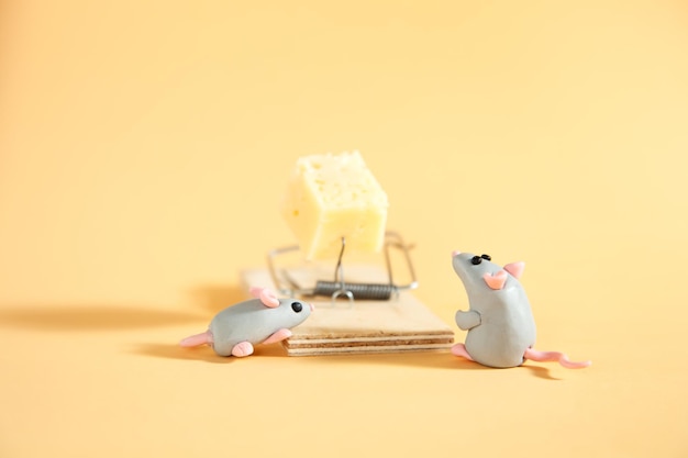 Piccoli topi grigi di plasticina guardano un pezzo di formaggio in una trappola per topi