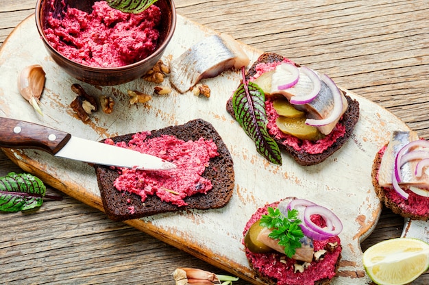 Piccoli tramezzini o bruschette con aringa salata, barbabietola e cipolle