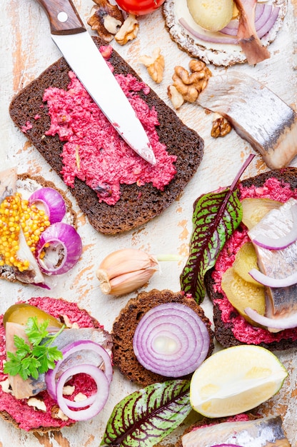 Piccoli tramezzini o bruschette con aringa salata, barbabietola e cipolle