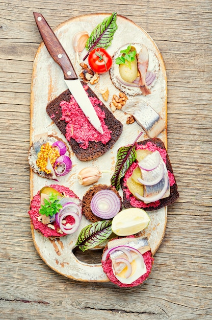 Piccoli tramezzini o bruschette con aringa salata e barbabietola.Panino aperto con aringa salata