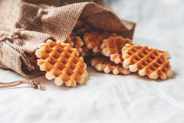 Piccoli waffle nel sacchetto di cotone su uno sfondo di tessuto bianco