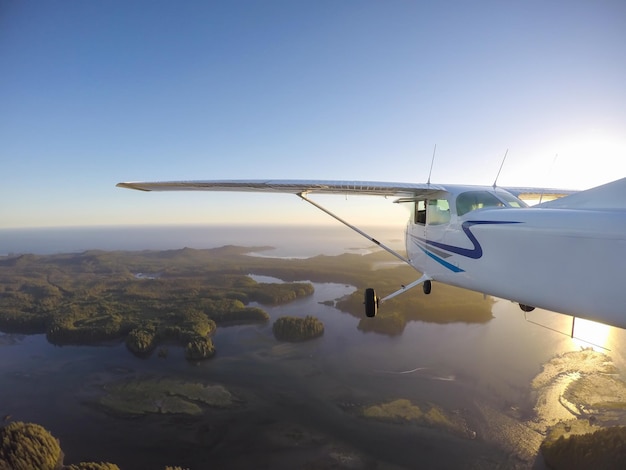 Piccolo aeroplano che vola sopra lo sfondo della natura del tramonto dell'Oceano Pacifico della costa occidentale