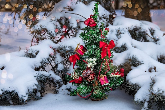 Piccolo albero di Natale decorato a festa in una foresta invernale innevata per Natale e Capodanno