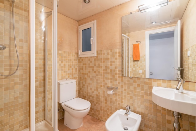 Piccolo bagno con wc doccia bidet e lavabo pareti con piastrelle in ceramica di un bel colore arancione