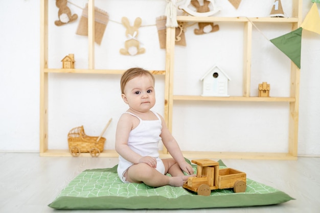 Piccolo bambino a casa nella stanza luminosa dei bambini che gioca con i giocattoli di legno il bambino a casa che gioca con una macchina da scrivere