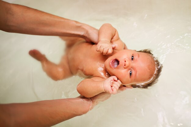 Piccolo bambino affascinante si bagna in acqua calda