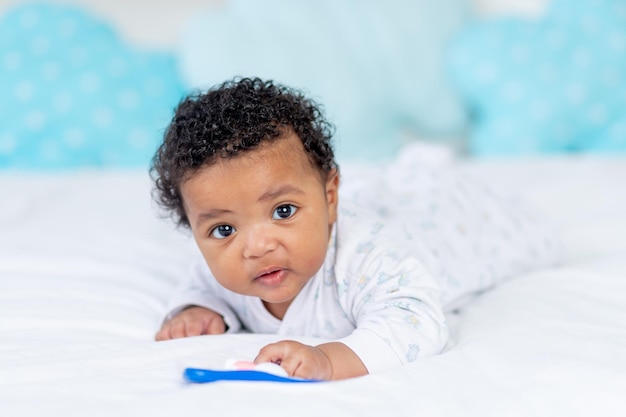 Piccolo bambino afroamericano in una culla nella camera da letto sdraiato sulla pancia con un sonaglio