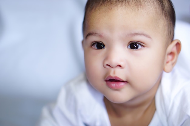 Piccolo bambino asiatico carino felicemente sdraiato sul lenzuolo blu il concetto di empatia adorabile