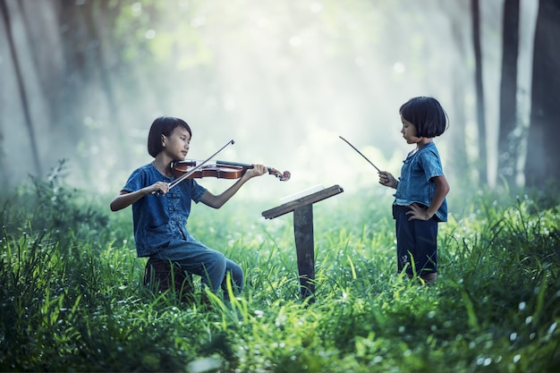 Piccolo bambino asiatico che gioca violino all&#39;aperto