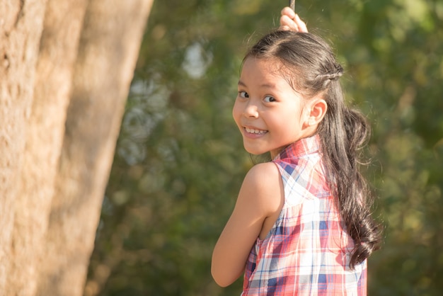 Piccolo bambino asiatico felice della ragazza che si diverte a giocare nel campo da giuoco nell'ora legale con il sorriso e il bambino femminile adorabile adorabile del fronte sorridente sano e divertente di risata.