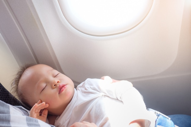 Piccolo bambino asiatico sveglio del bambino del bambino di 18 mesi / 1 anno che dorme sull'aeroplano con lo spazio della copia