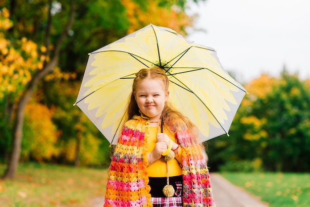 Piccolo bambino, bambina che ride e gioca in autunno sulla passeggiata nella natura all'aperto