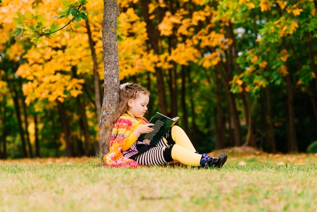 Piccolo bambino, bambina che ride e gioca in autunno sulla passeggiata nella natura all'aperto