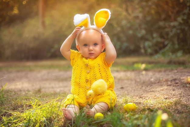 Piccolo bambino carino con orecchie da coniglio il giorno di Pasqua La ragazza cerca le uova di Pasqua sul prato Ragazza con uova di Pasqua e pollo sotto i raggi del sole al tramonto