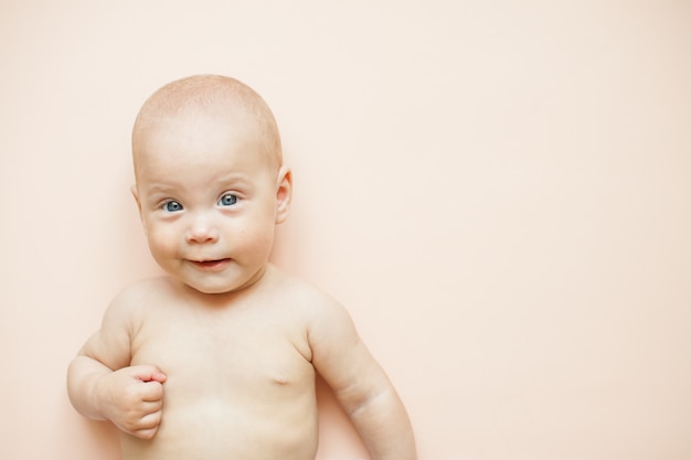 Piccolo bambino carino si trova su uno sfondo rosa chiaro.